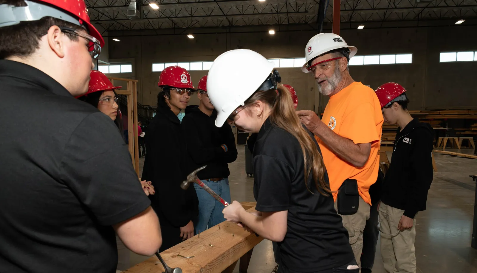 An apprenticeship instructor guiding students through a hands-on carpentry task
