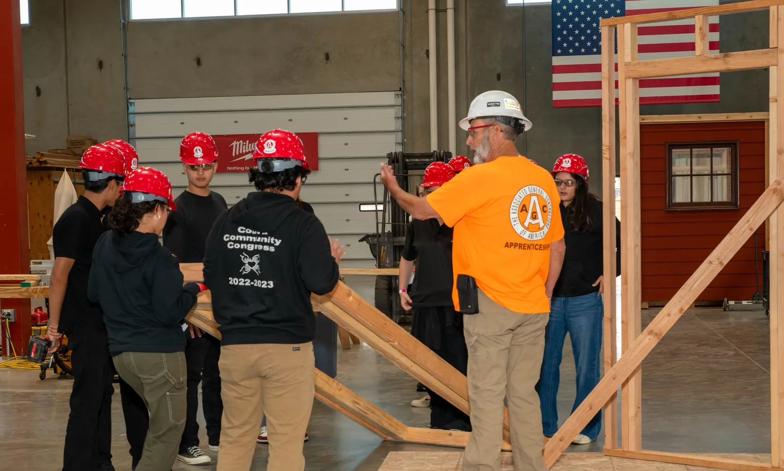 High school students in hard hats framing a wall with a trades instructor at a San Diego training centre